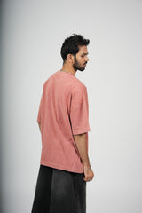 Man wearing a pink t-shirt and black pants on a gray background