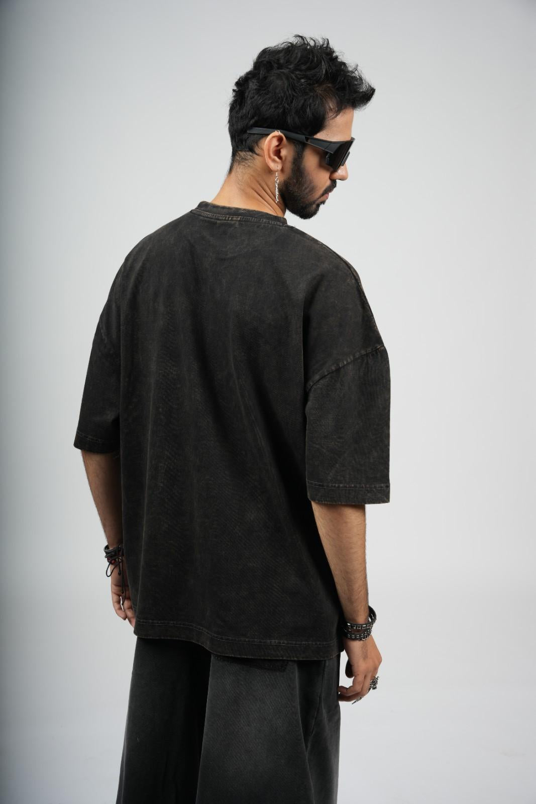 Man wearing a black t-shirt and pants on a plain background
