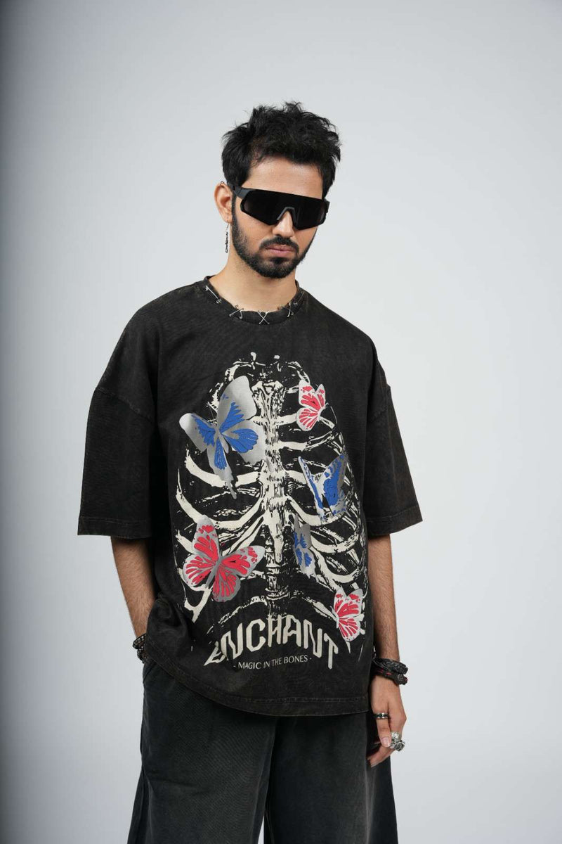 Person wearing a black t-shirt with butterfly and skeleton design on a plain background