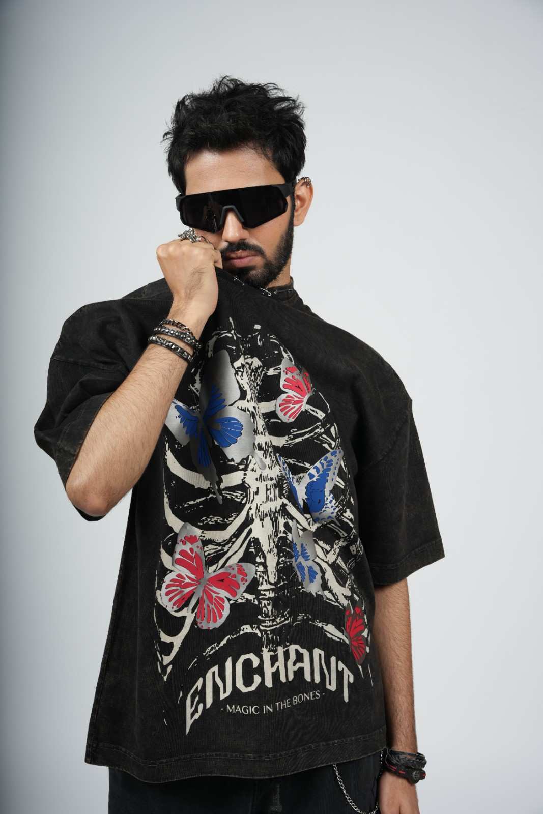 Person wearing a black t-shirt with butterfly design and 'Enchant' text, posing against a plain background.