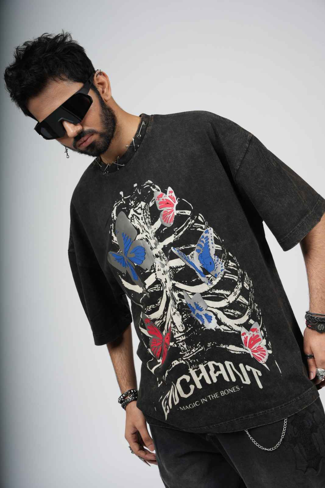 Man wearing a black t-shirt with colorful butterfly design and 'Enchant' branding.