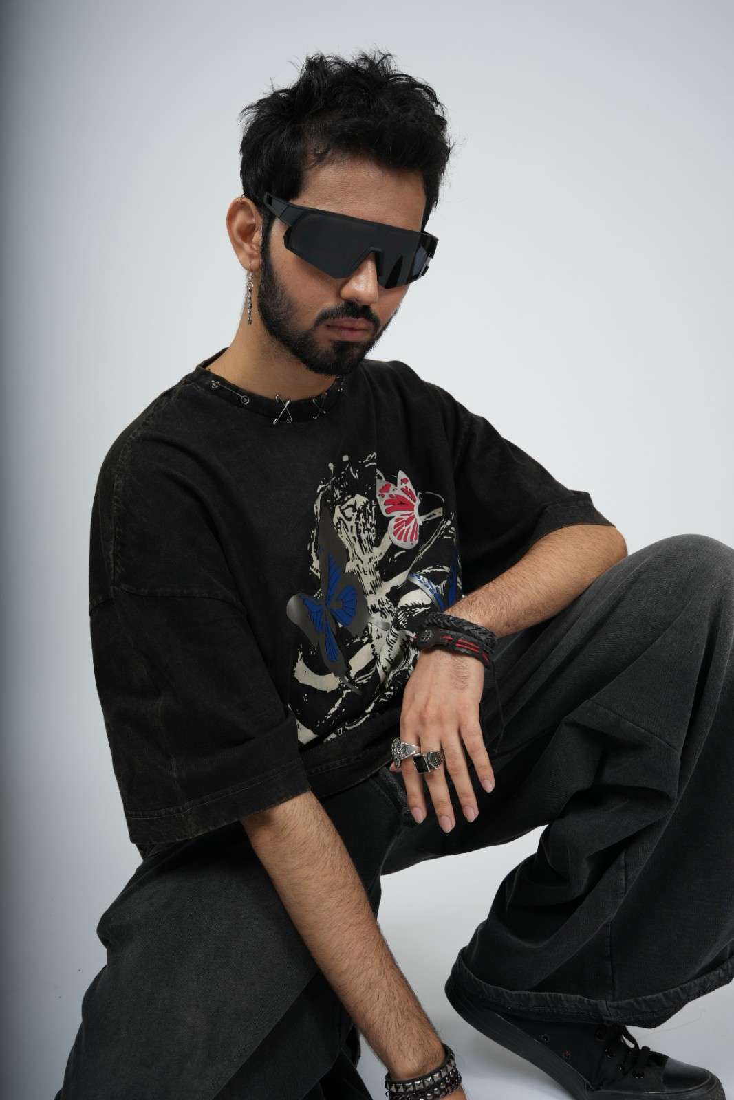 Man wearing a black graphic t-shirt and sunglasses against a light gray background
