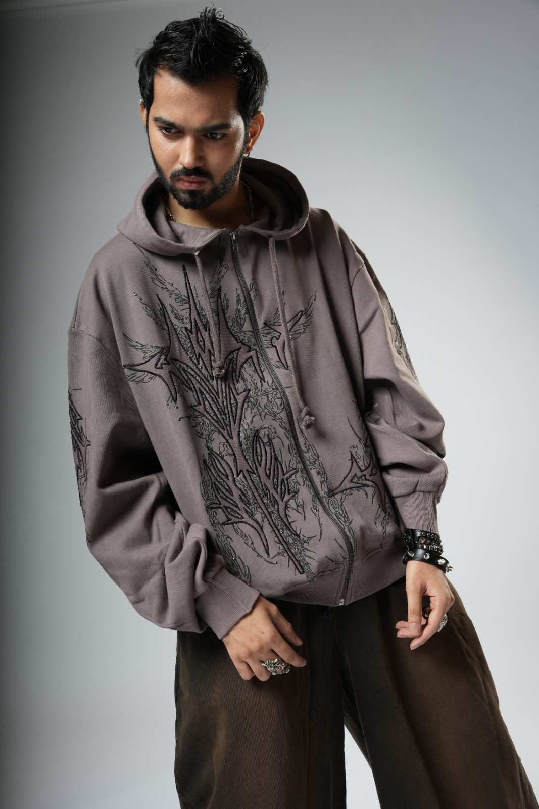 Man wearing a gray hoodie with a floral design on a gray background