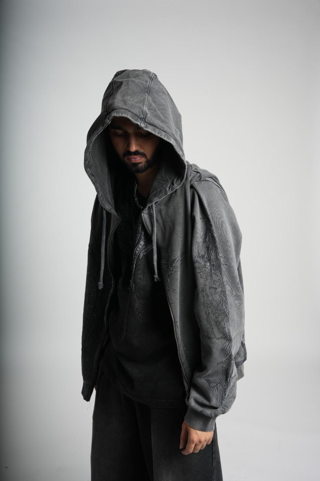 Person wearing a gray hooded jacket against a plain background