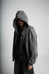 Person wearing a gray hooded jacket against a plain background