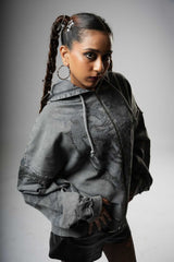 Woman wearing a gray hoodie with lace details against a gray background