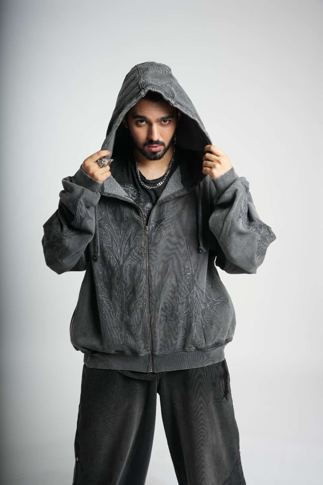 Person wearing a gray hoodie and pants on a light gray background
