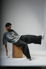 Man sitting on a wooden block with one leg raised against a plain background