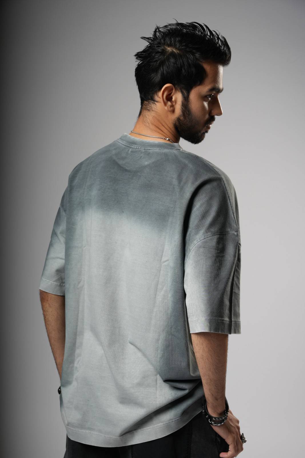 Man wearing a gray t-shirt against a gray background