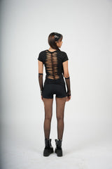 Person wearing a black outfit with sheer back design on a white background
