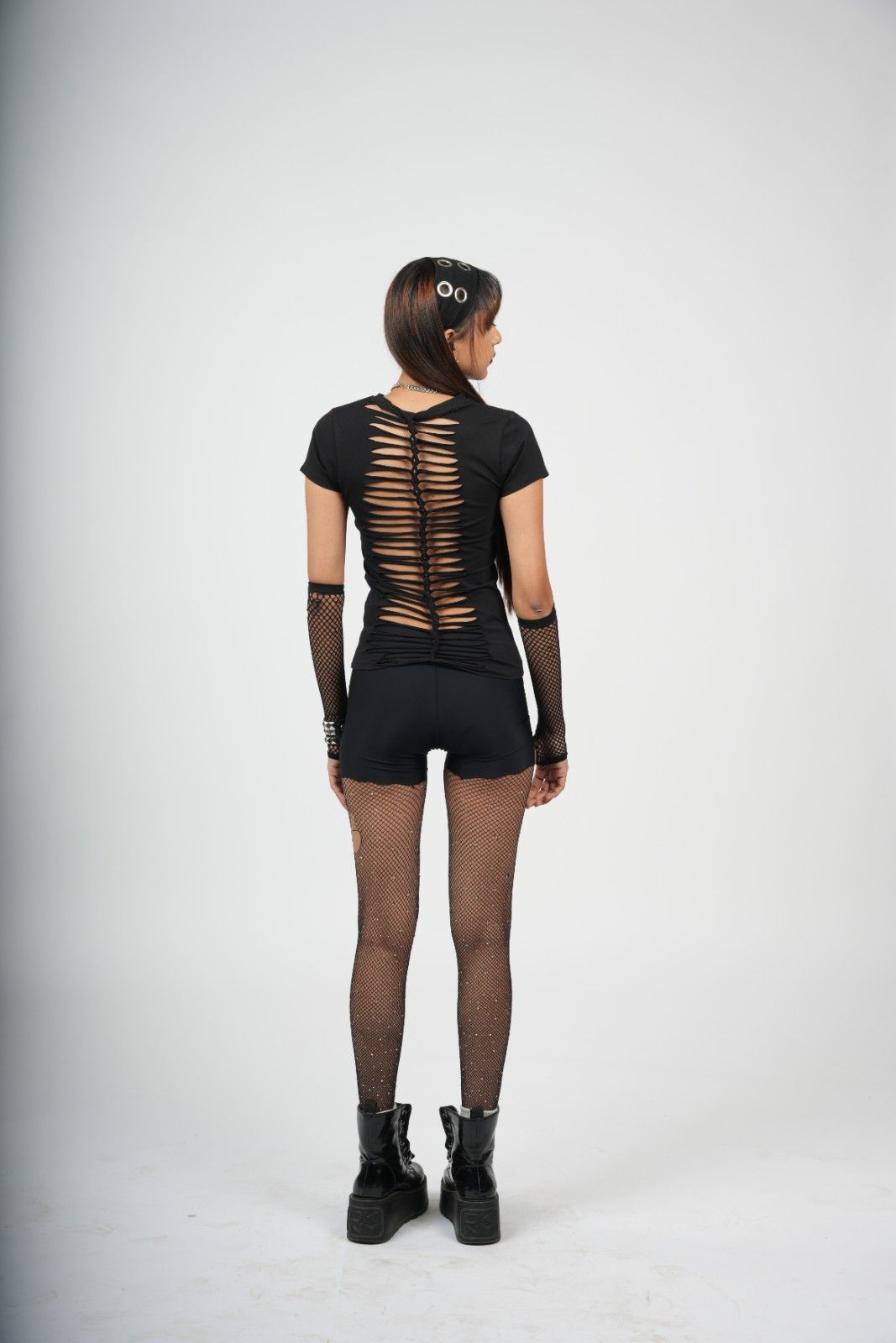 Person wearing a black outfit with sheer back design on a white background
