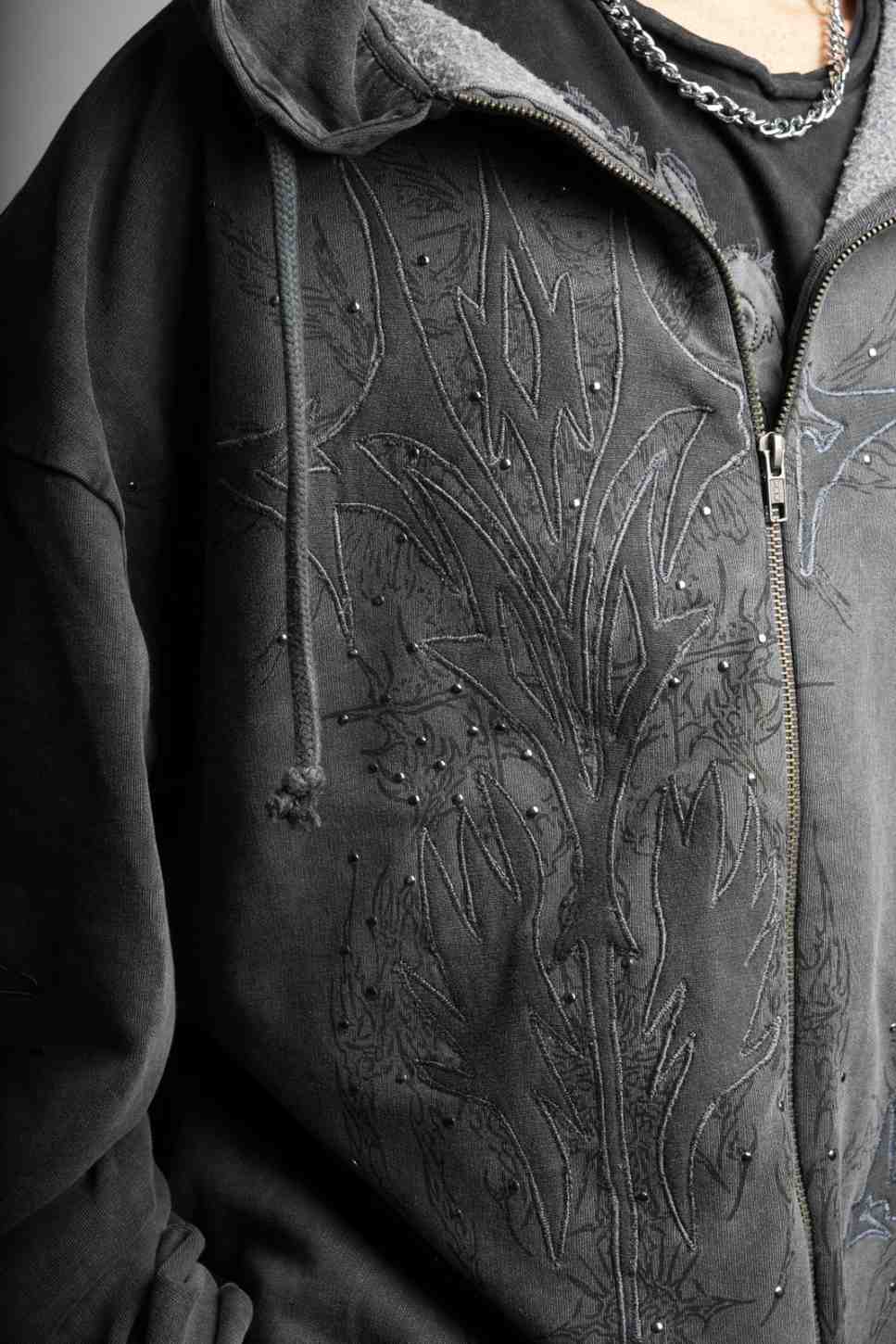 Close-up of a dark gray hoodie with intricate floral embroidery on the chest.