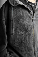 Close-up of a dark gray hoodie with intricate floral embroidery on the chest.