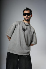 Man wearing a gray t-shirt with a black eagle design and sunglasses on a gray background