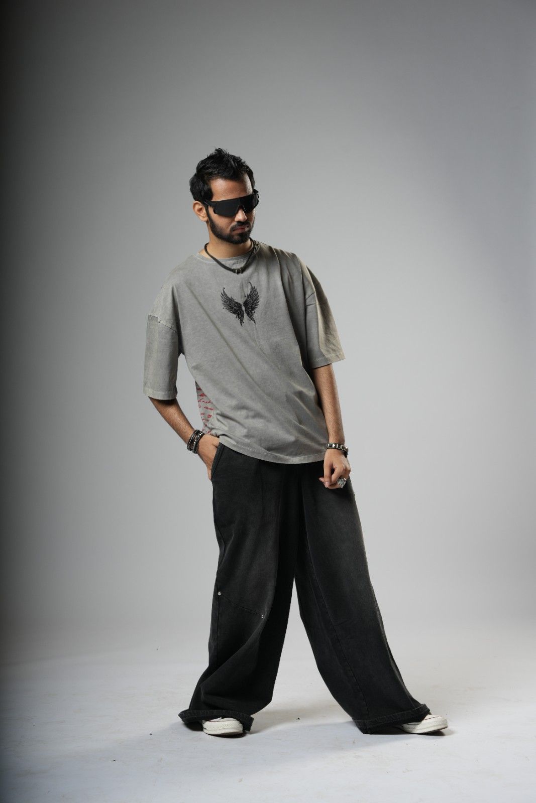 Man wearing a gray t-shirt and black pants on a plain background