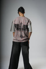 Person wearing a patterned shirt with a cross design on a gray background
