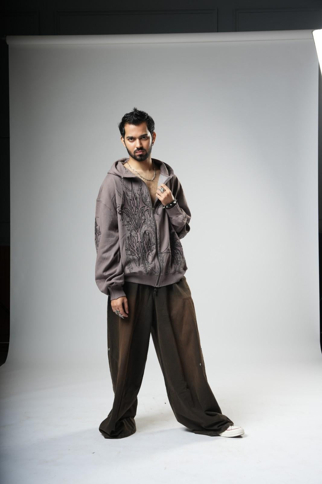 Man wearing a gray hoodie and brown pants on a white background