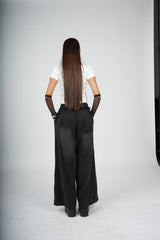Person wearing a white shirt and black wide-leg pants on a plain background
