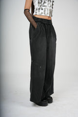 Person wearing black wide-leg pants and a white crop top with text on a plain background