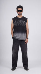 Man wearing a black sleeveless shirt with white text and dark pants on a white background
