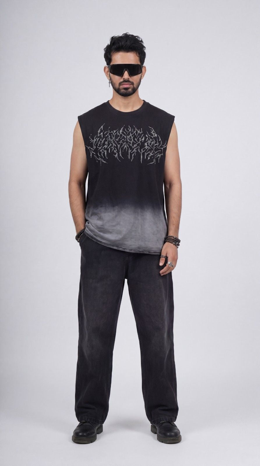 Man wearing a black sleeveless shirt with white text and dark pants on a white background