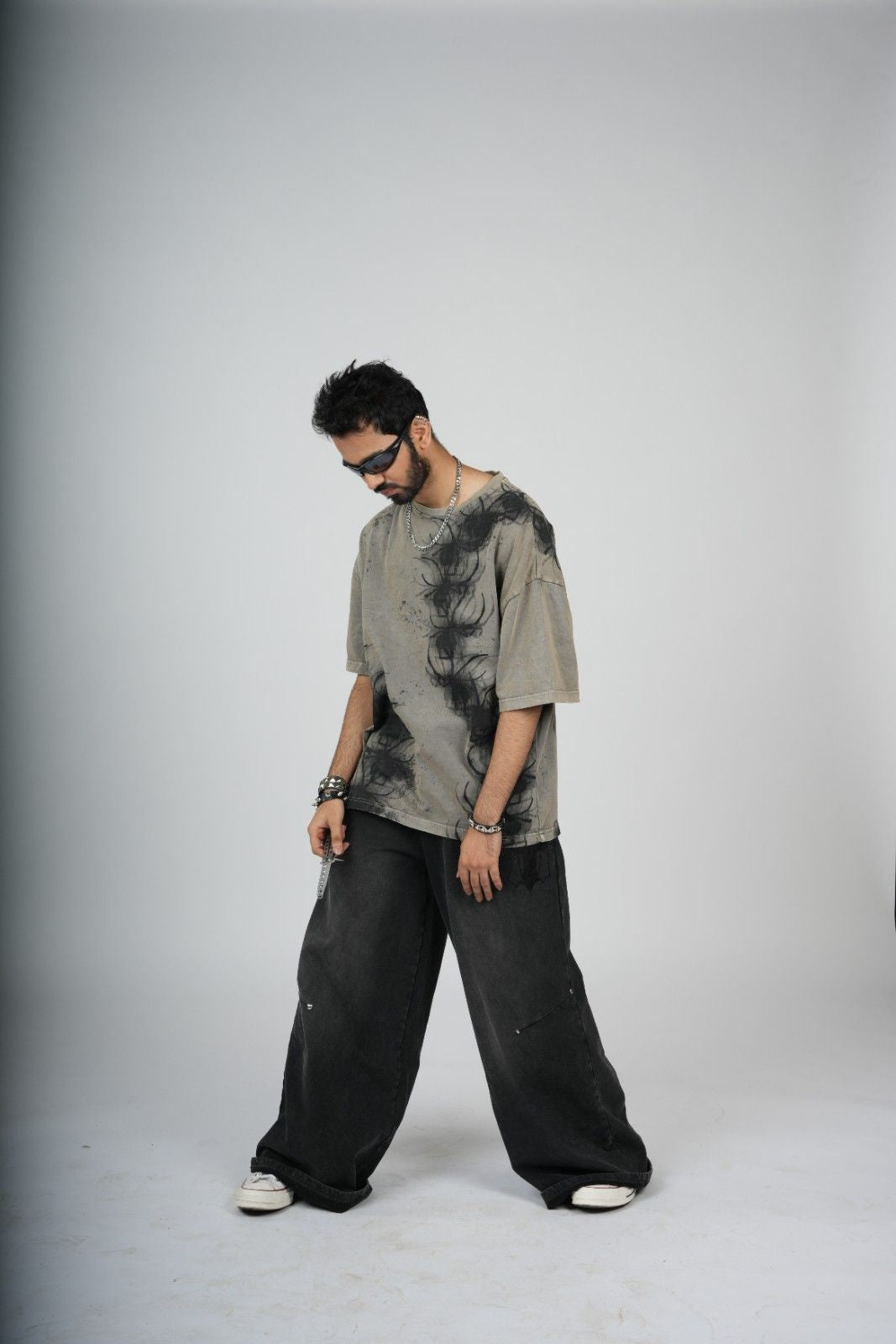 Person wearing a tie-dye shirt and wide-leg pants on a plain background