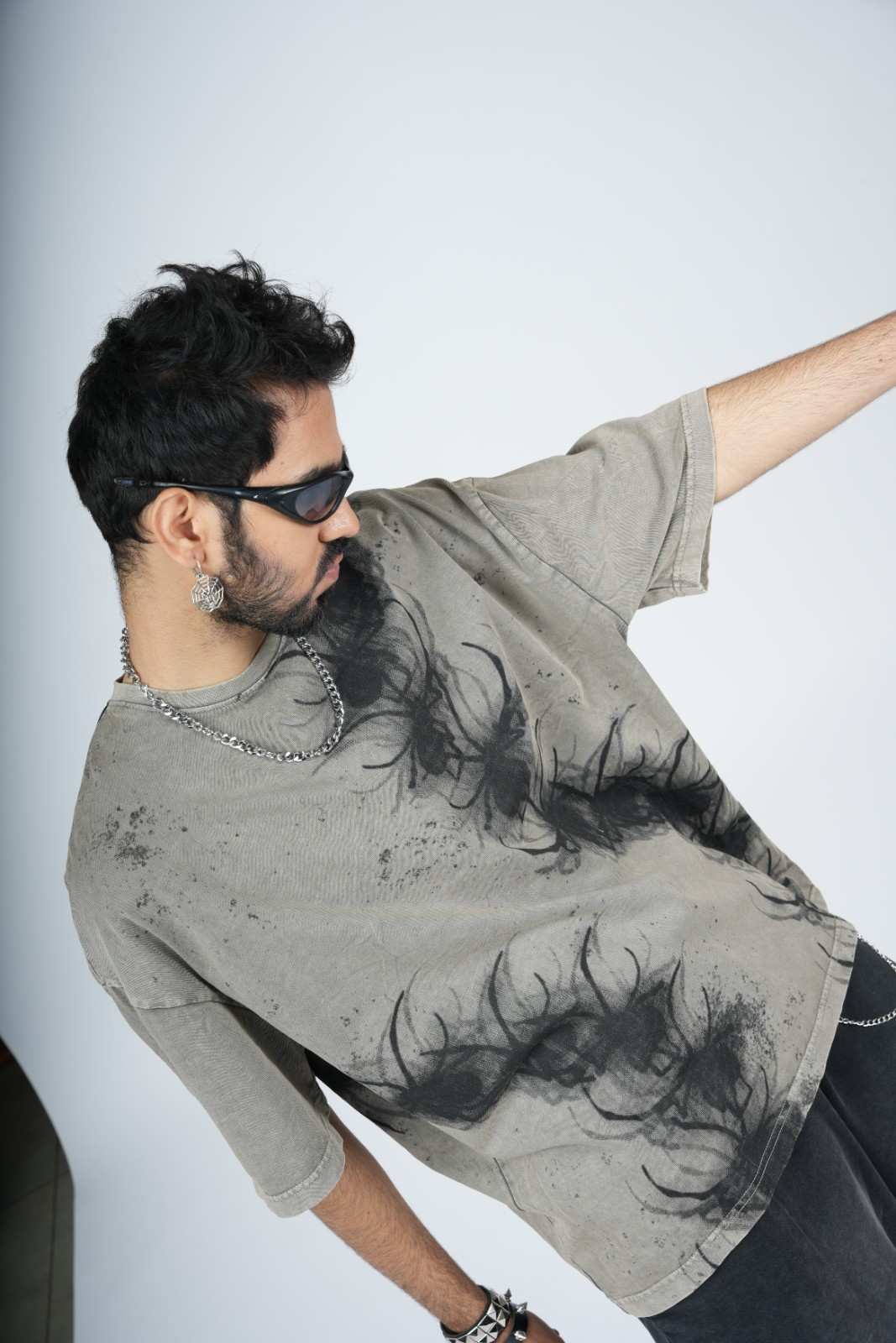 Man wearing a gray t-shirt with black patterns against a white background