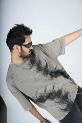Man wearing a gray t-shirt with black patterns against a white background