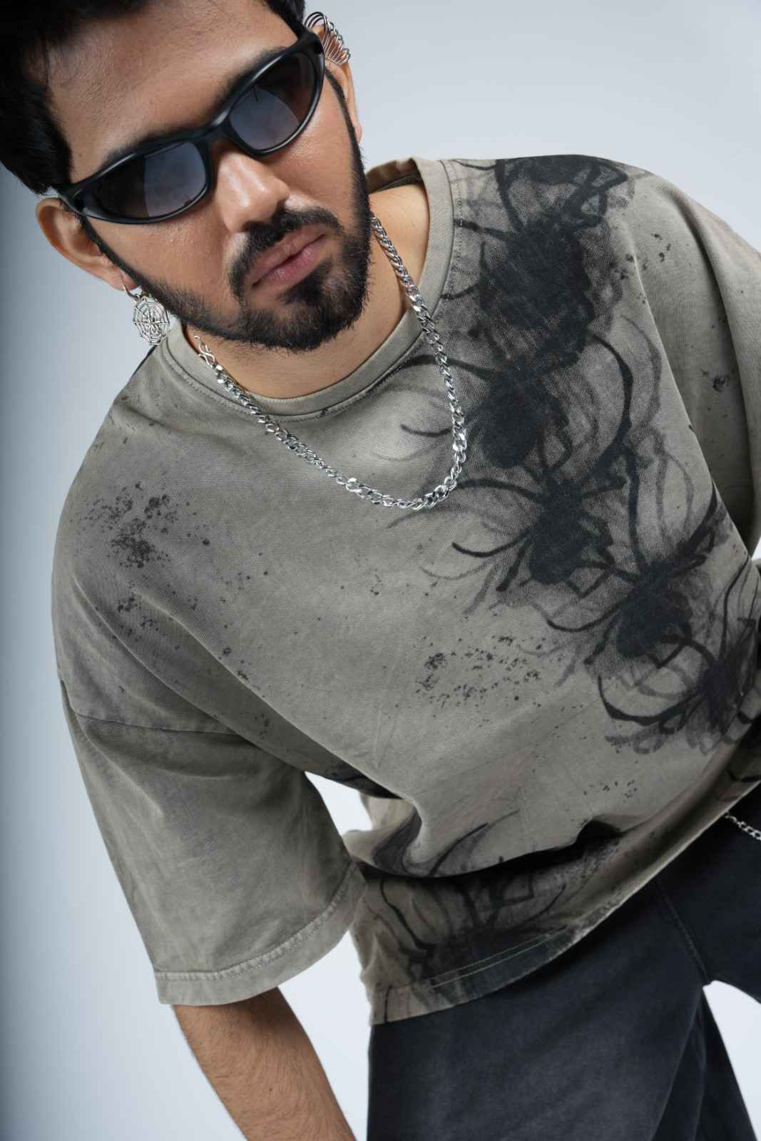 Man wearing a gray t-shirt with a spider design on a light gray background